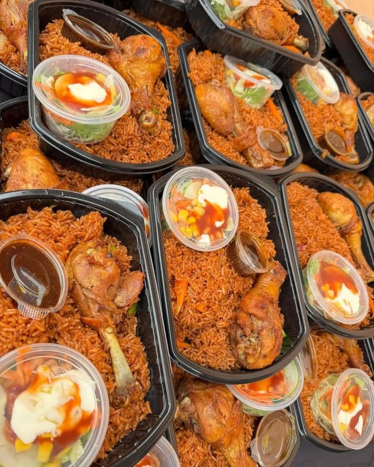 A tray of jollof rice with plantain and peppered meat
